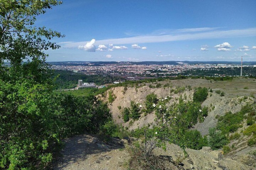 A hilly landscape with a city in the distance, a dirt path, and a clear sky. 4