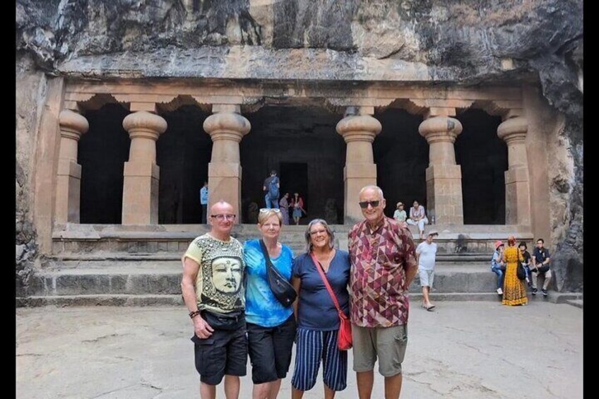A group of people standing in front of a large, ancient stone structure with columns. 1