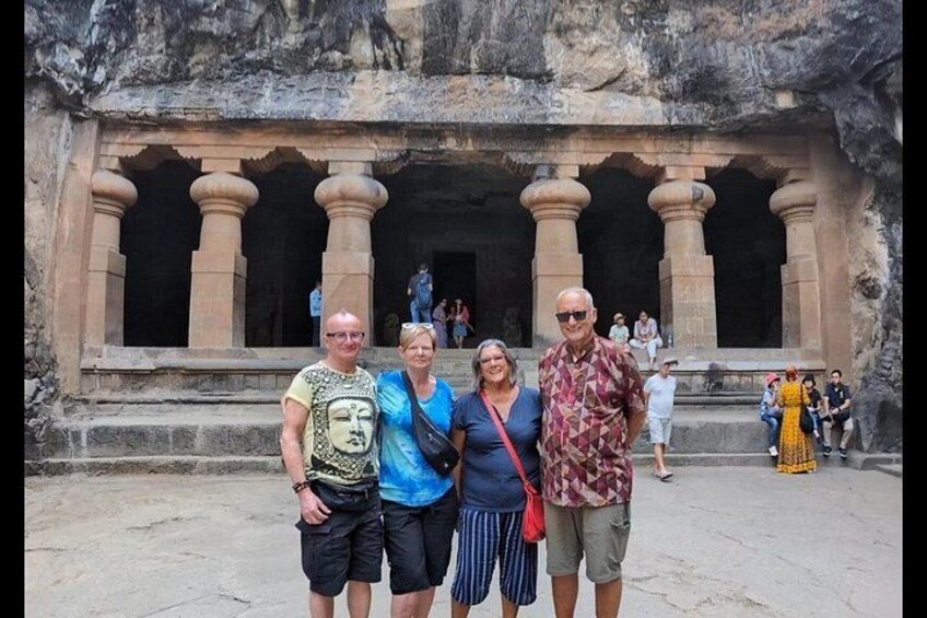 A group of people standing in front of a large, ancient stone structure with columns. 1