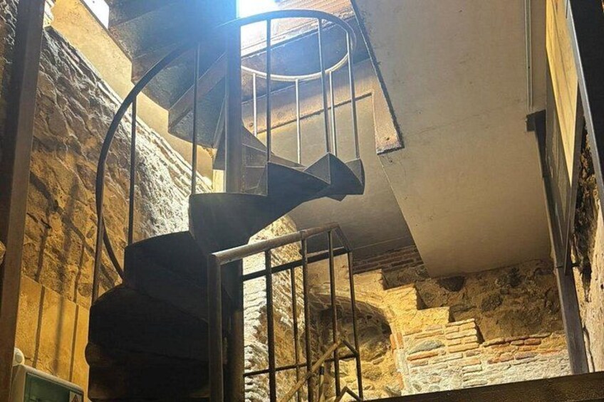 Un escalier en colimaçon dans un intérieur aux murs de pierre. 5