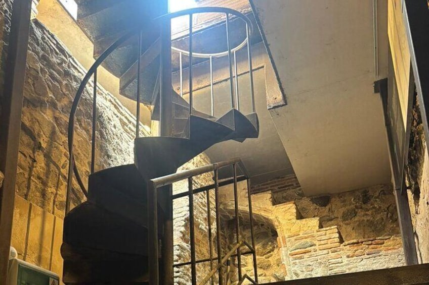 A spiral staircase in a stone-walled building. 5