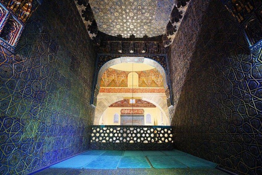 An ornate interior with intricate geometric patterns on the walls and a central arched doorway. 3