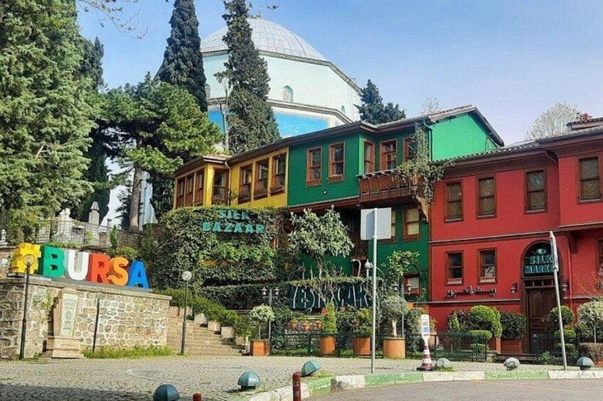 A colorful building with a sign reading 'BURSA' and a dome in the background. 1