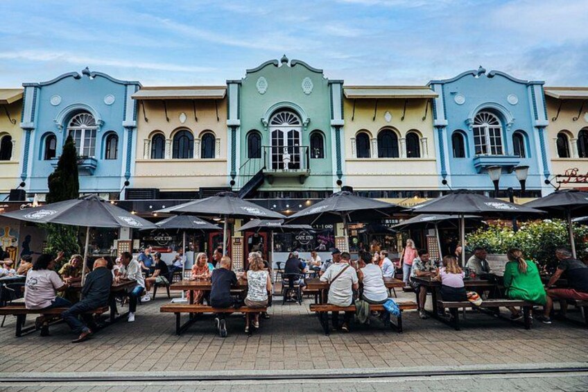 A colorful building with outdoor seating and people dining. 1