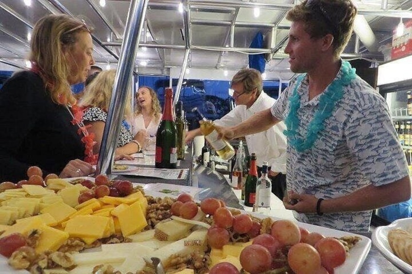 A buffet table with various cheeses, fruits, and bottles. 5
