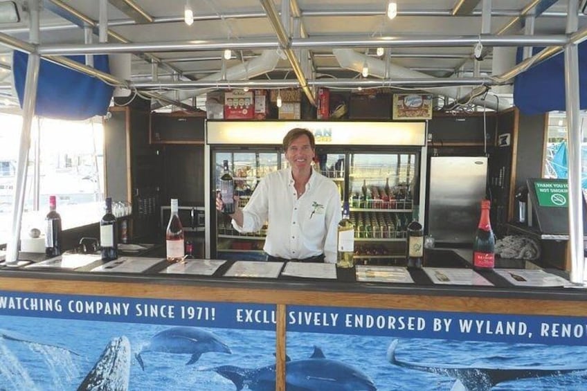 A bar area with a bartender, a counter with various bottles, and a backdrop featuring a whale. 2