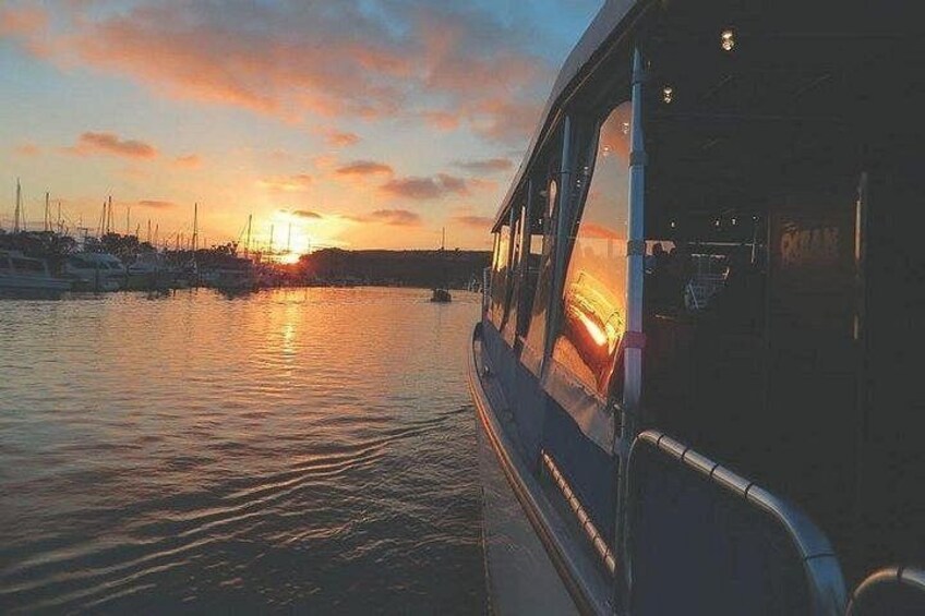 Ein Sonnenuntergang über einem Yachthafen mit Booten und einer Fähre. 1