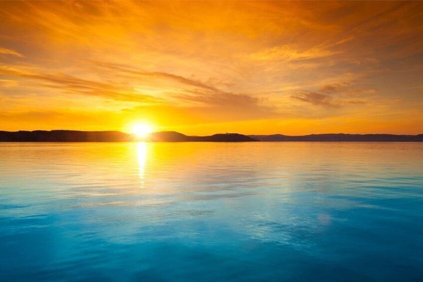 A sunset over a calm body of water with a clear horizon. 3