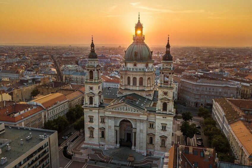Une vue urbaine mettant en valeur une cathédrale imposante, dotée de deux tours et d’un dôme, se détachant sur un ciel au coucher du soleil. 3