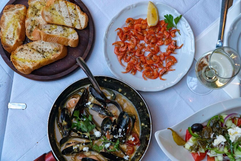 A table with various dishes including bread, shrimp, mussels, and a salad. 2