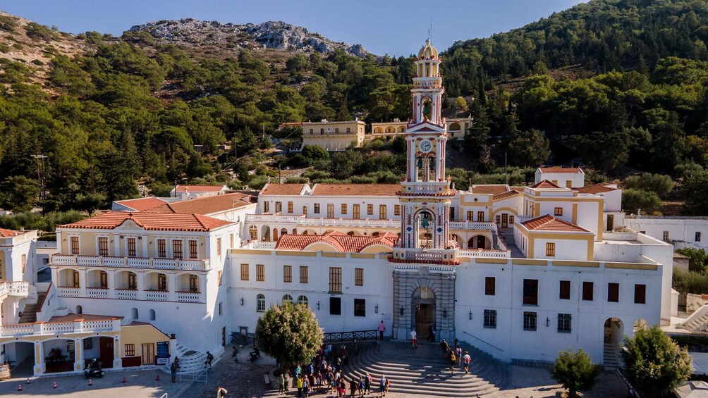 A white building with a clock tower, surrounded by trees and other buildings. 5