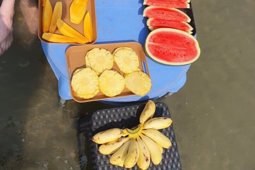 A table with sliced fruits including pineapple, mango, and watermelon. 1
