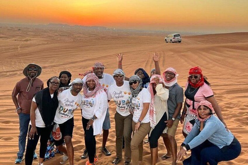 A group of people in a desert landscape with a sunset in the background. 5