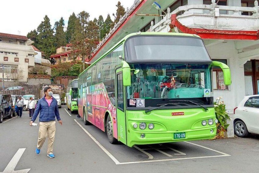 A green bus parked in a parking lot with a building in the background. 5