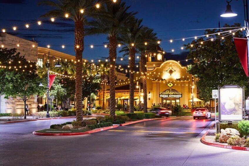 A brightly lit hotel entrance with palm trees and string lights. 3