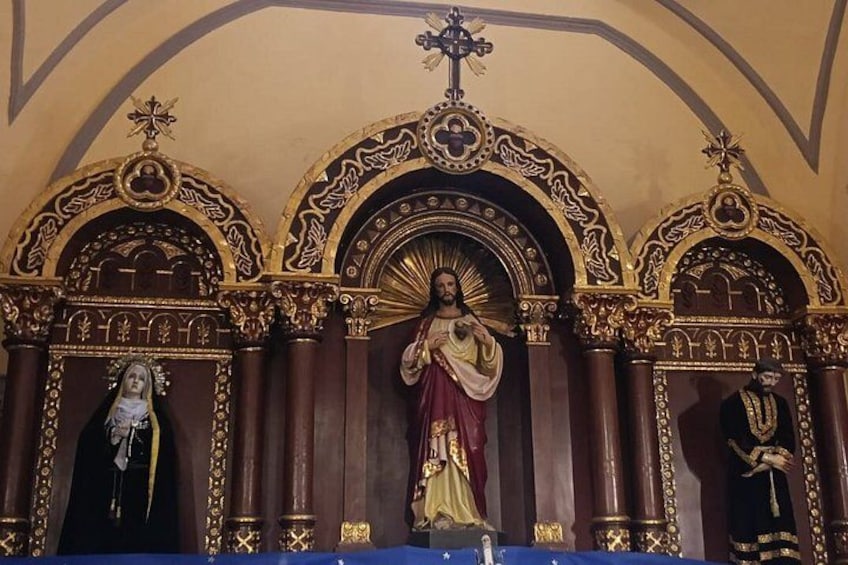 An ornate religious iconostasis with three figures, including a central figure in a red and gold robe, flanked by two other figures in black and gold. 4