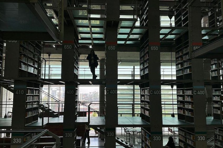 A library interior with multiple floors, bookshelves, and a person climbing stairs. 5