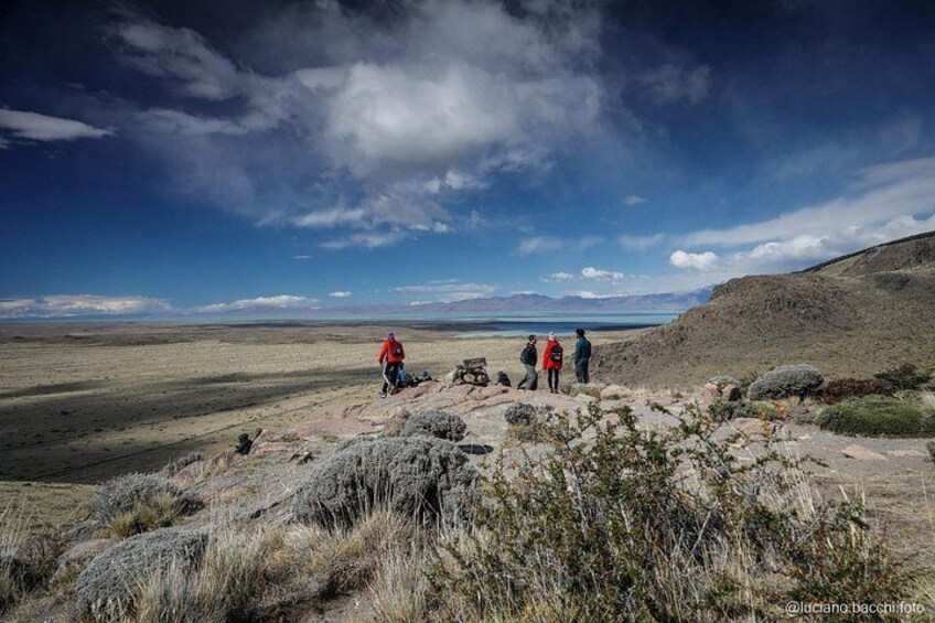A group of people hiking on a rocky terrain with a vast landscape in the background. 4