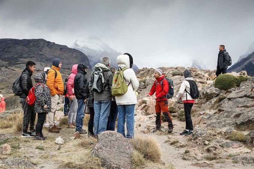 A group of hikers on a rocky mountain trail with snow-capped peaks in the background. 3