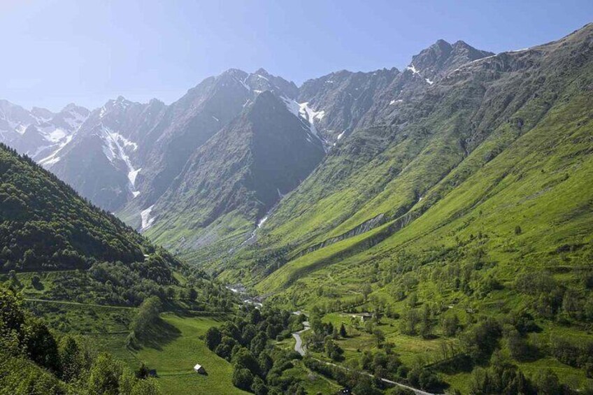 A valley with lush greenery, a winding road, and snow-capped mountains in the background. 3