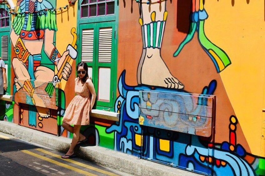 A person walking past a colorful mural with abstract designs and a bus stop. 3