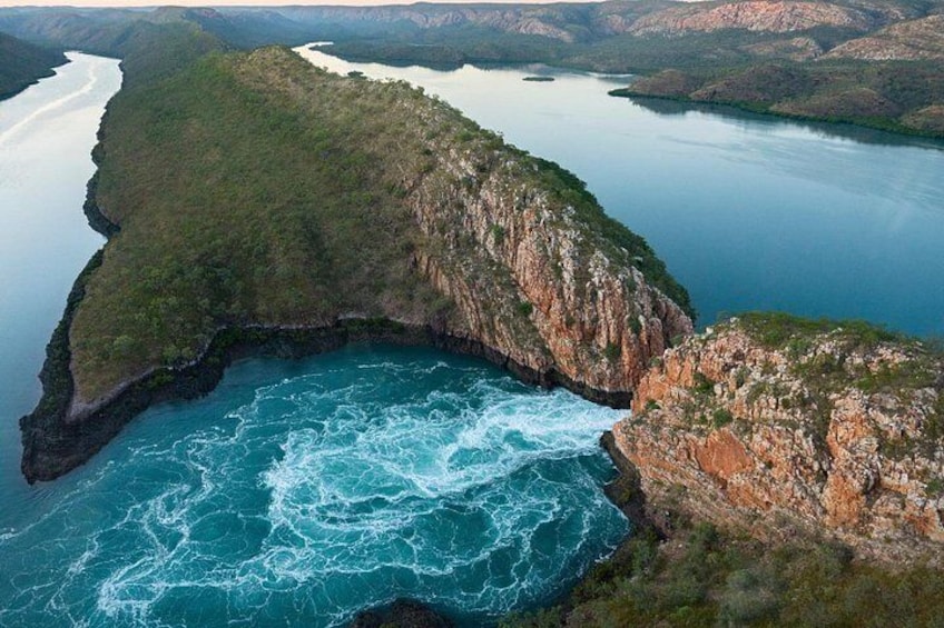 Un paisaje costero con un canal estrecho, acantilados rocosos y una extensa masa de agua. 3