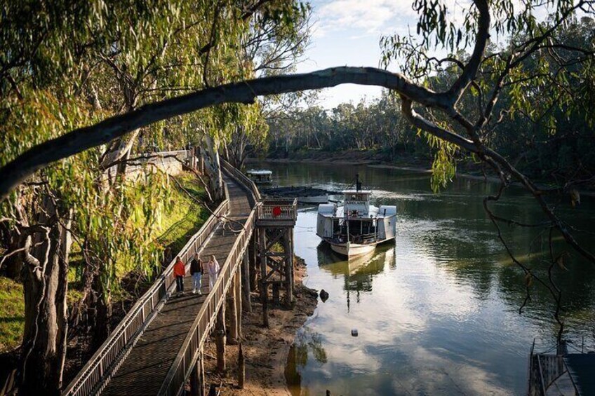 A wooden bridge over a river with a boat docked at the end. 3
