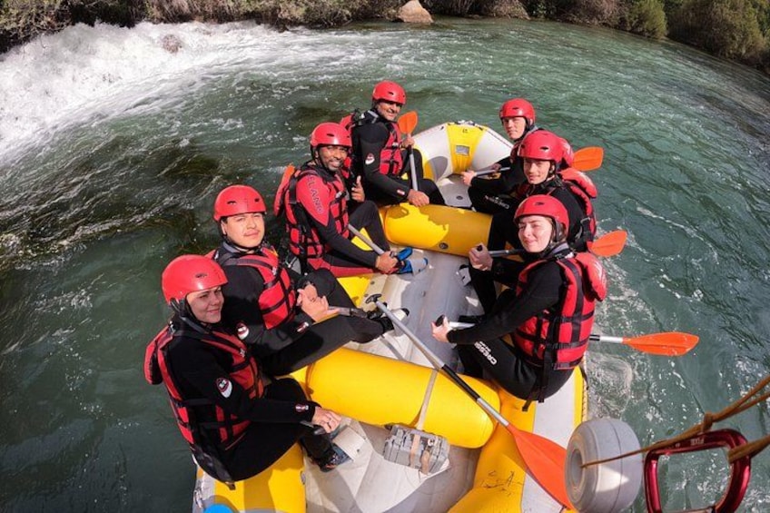 A group of people in a yellow raft on a river, wearing red helmets and life jackets. 5
