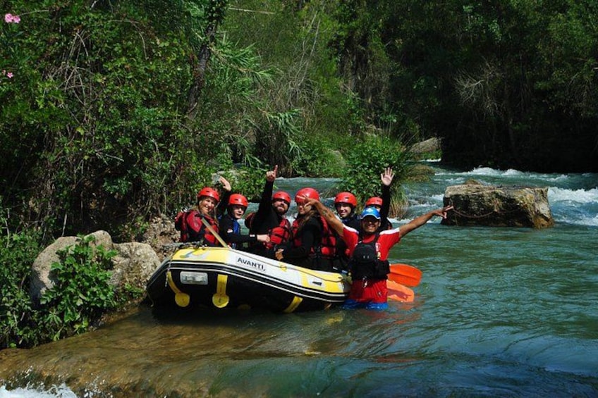 A group of people in a raft on a river surrounded by greenery. 3