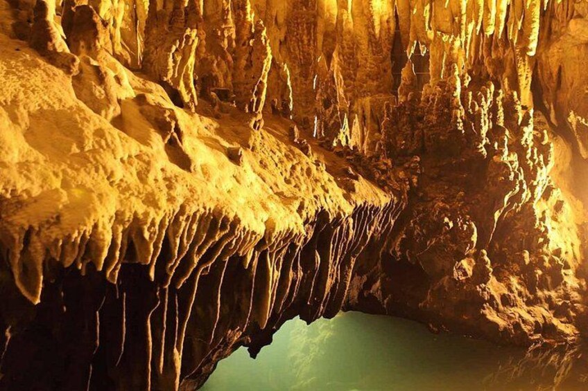 A cave with stalactites and stalagmites, a pool of water, and a narrow passageway. 3