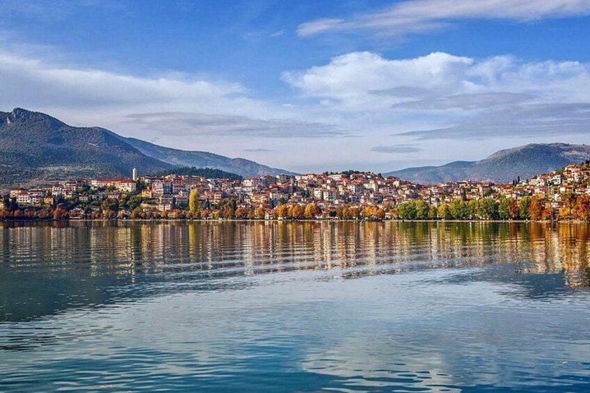 A calm lake with a town and mountains in the background. 3