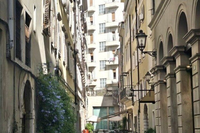 A narrow street flanked by historic buildings with balconies and arched windows. 4