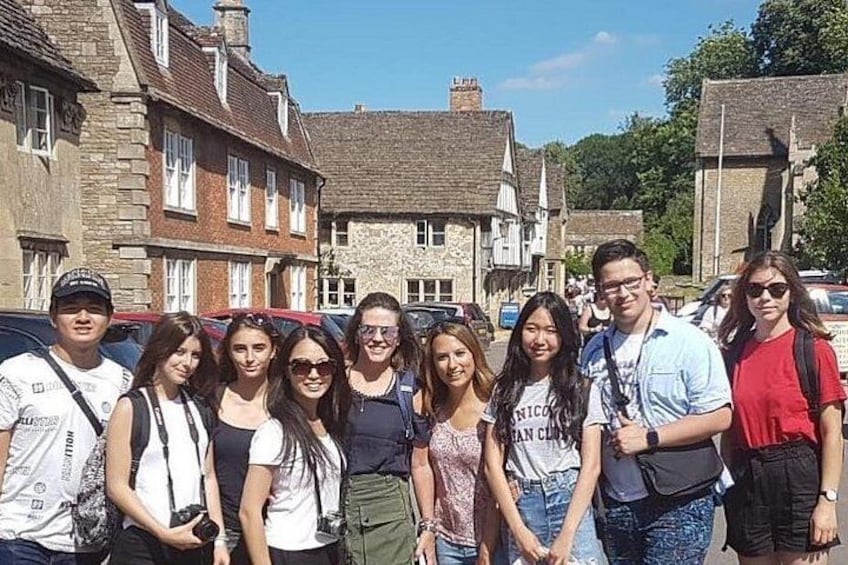 A group of people standing in front of stone buildings with a clear sky. 3