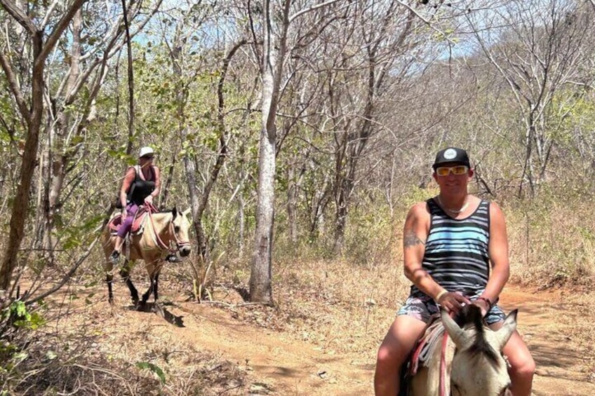 A person riding a horse on a dirt path in a wooded area. 2