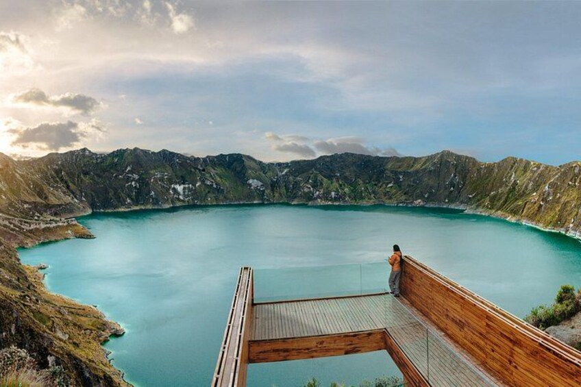 A wooden viewing platform overlooking a turquoise lake surrounded by mountains. 4