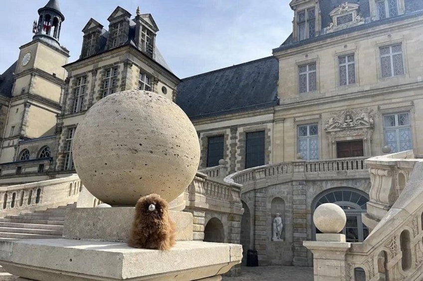 A historic building with a large spherical stone structure and a small dog on a platform. 4