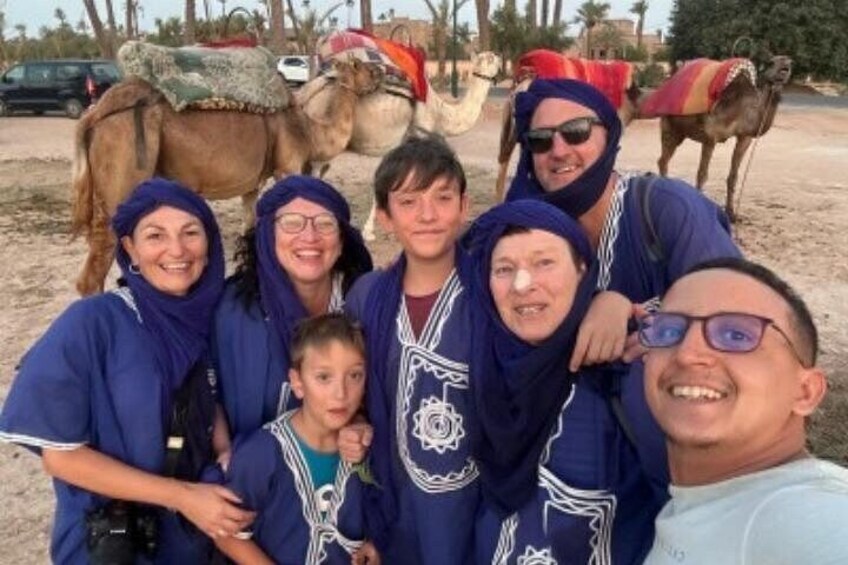 A group of people in traditional attire with camels in the background. 4