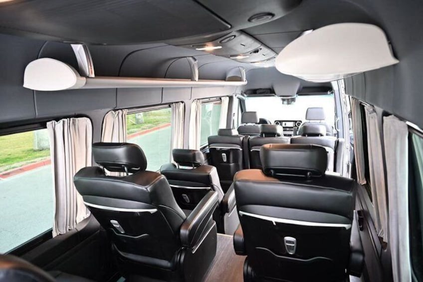 A vehicle interior with multiple rows of seats, a steering wheel, and a dashboard. 2