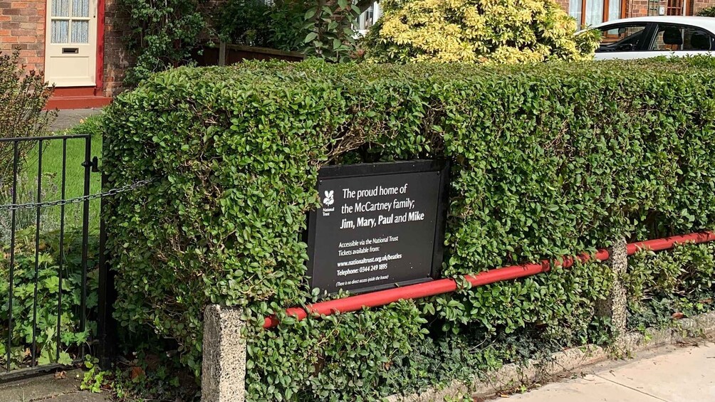A black sign on a hedge stating it's the home of the McCartney family. 4