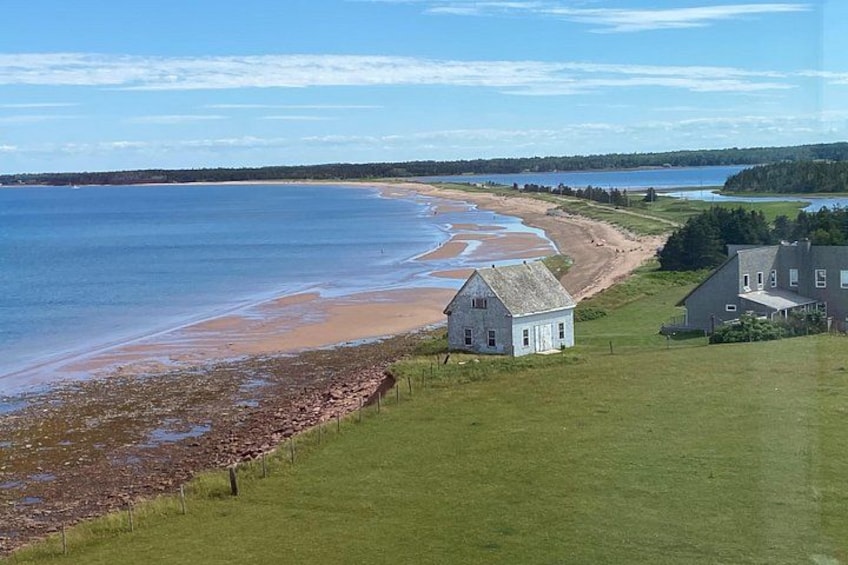 Et kystlandskab med strand, græsarealer og to huse. 3