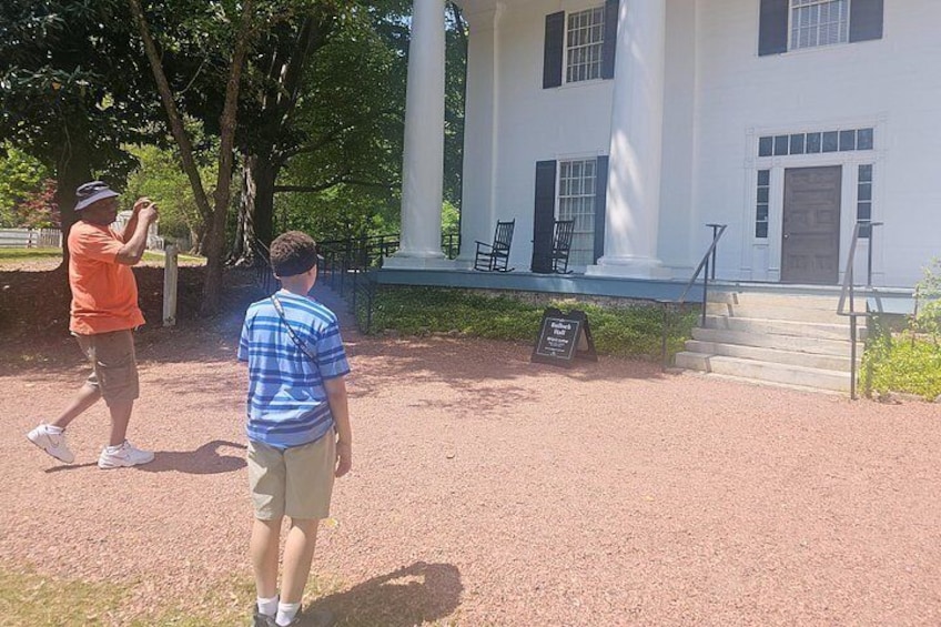 A historic building with columns, a paved area, and a signboard. 5