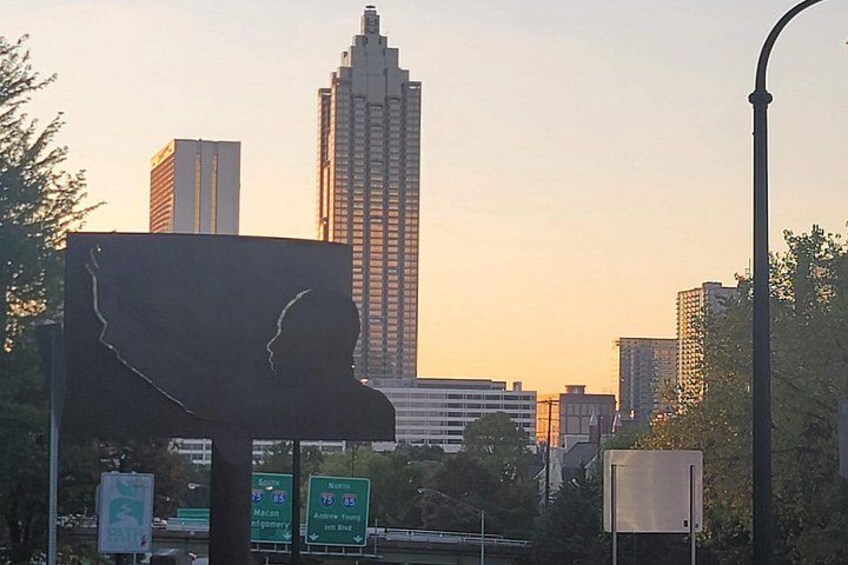 A cityscape with a prominent building, street signs, and a silhouette sculpture. 4