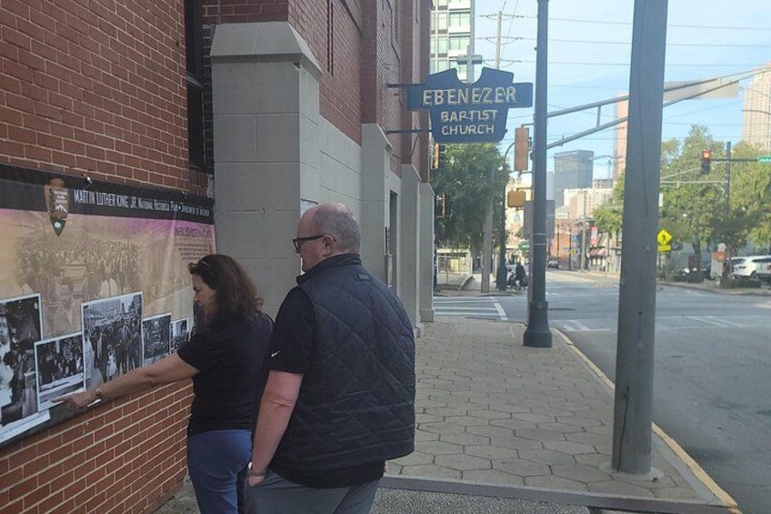 A brick building with a sign for Ebenzer Baptist Church and a display of photographs. 2