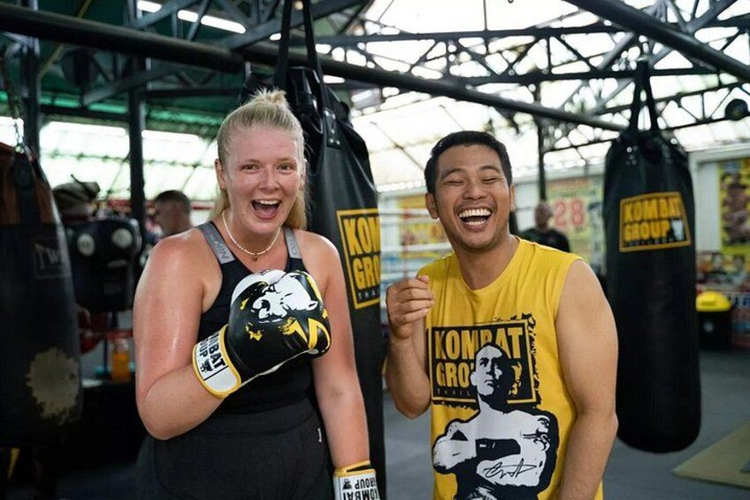 Two people in a gym with boxing gloves and a punching bag. 1