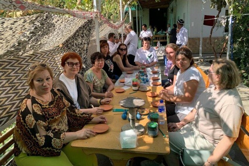 A group of people seated around a table outdoors, engaged in a meal or activity. 4