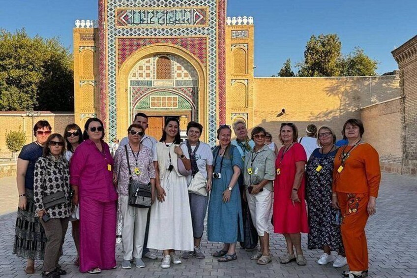 A group of people standing in front of a historic building with intricate tile work and a large archway. 5