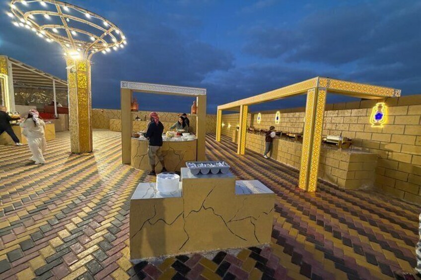 An outdoor area with patterned flooring, a central table, and illuminated structures. 2