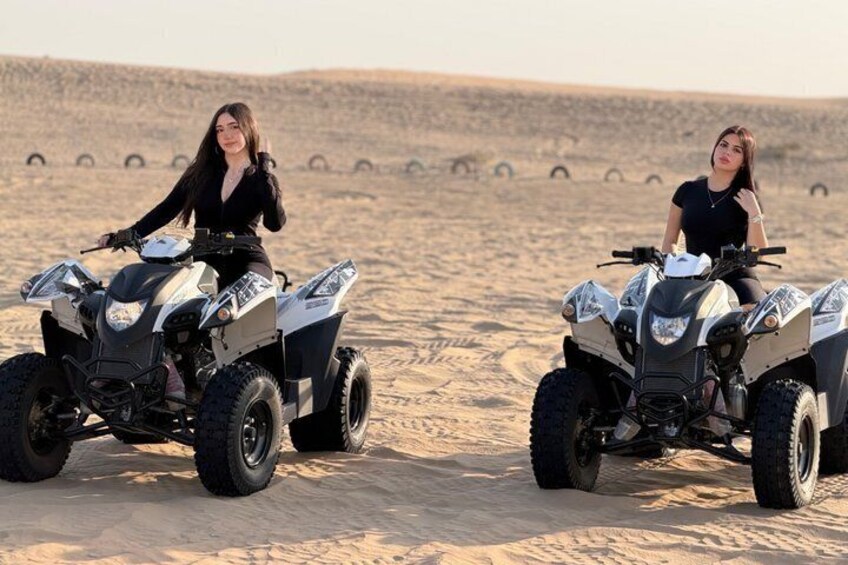 Two people on ATVs in a desert with tire tracks. 5