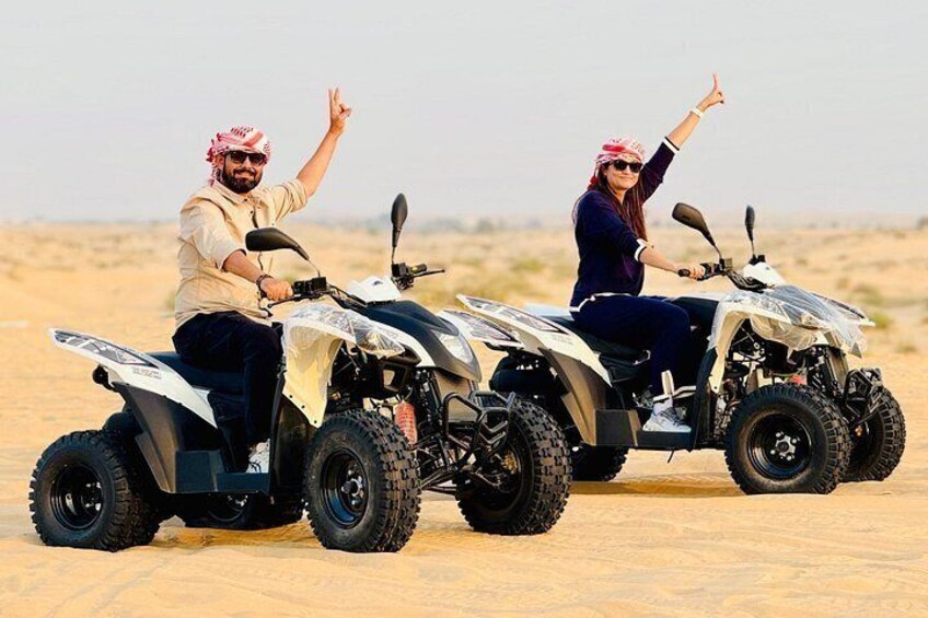 Two people on quad bikes in a desert landscape. 4