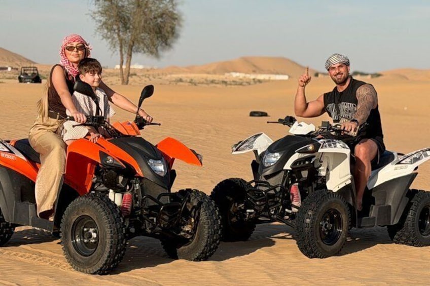 Two ATVs in a desert with sand dunes in the background. 1